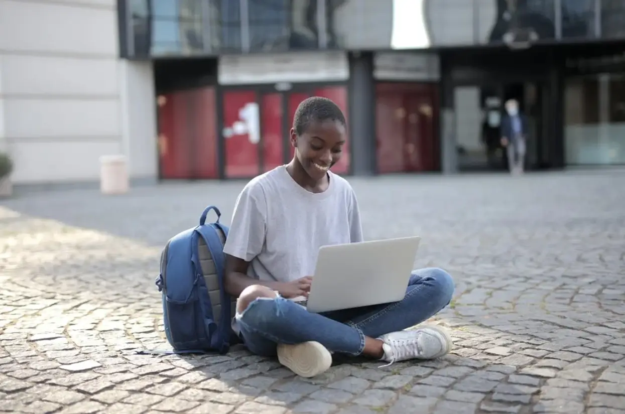 A teacher helping a student with their work on a laptop.